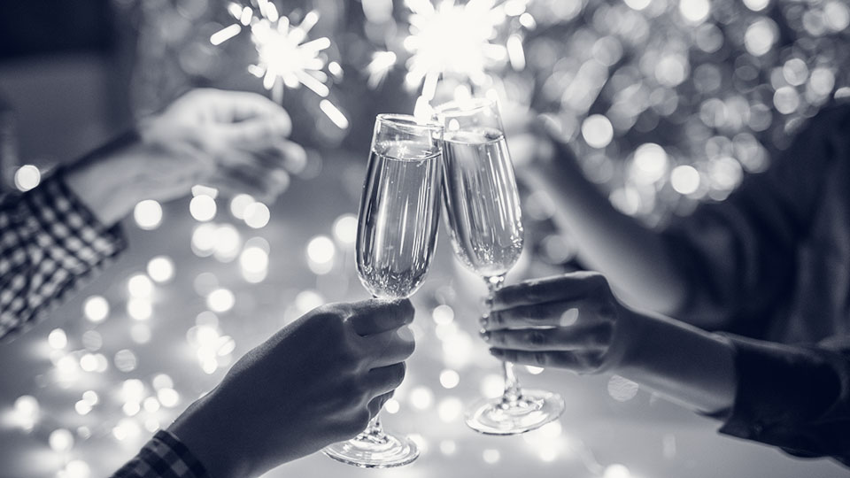 Hands of couple with flutes of champagne and their friends with lights